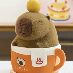 Flauschiges braunes Capybara Kuscheltier mit Orange auf dem Kopf im abnehmbaren orangefarbenen Kaffeebecher