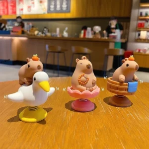 Vier verschiedene Wackelkopf Capybara Figuren mit Federbasis und Maßen: Vogel, Sprössling, Orange und Blüte