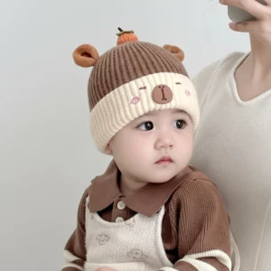 Baby trägt zweifarbige gestrickte Capybara Beanie mit niedlicher orangefarbener Persimonen-Dekoration auf der Krone