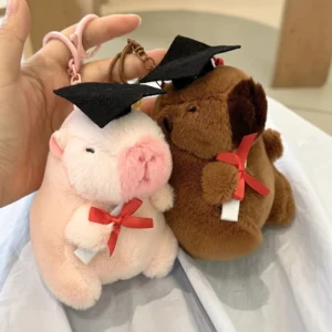 Brauner und rosafarbener capybara plüsch schlüsselanhänger als abschluss geschenk mit diplom und mütze