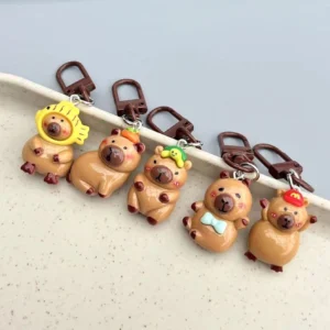 5-teiliges Set aus glänzenden Harz Capybara Anhänger in einer Reihe, mit einzigartigen Accessoires: Fisch-Kapuzenhut, Kaki, grüne Blättermütze, blaue Fliege und rote Baseballkappe