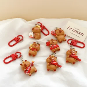 Aufsicht auf 6-teiliges Set aus glänzenden Resin Capybara Anhängern mit roten Sport- und Musikaccessoires wie Gitarren, Tennisschläger und Kopfhörern