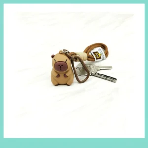 Detailaufnahme von 3D PVC Capybara Taschenanhänger mit praktischem Seil und Karabiner an brauner Tasche