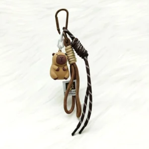 Nahaufnahme von 3D PVC Capybara Anhänger mit Seil und Metallkarabiner befestigt an brauner Ledertasche