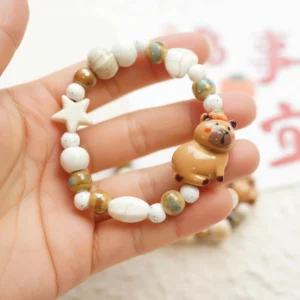 Detailansicht des elastischen Keramik Capybara Armbands mit handbemaltem Capybara-Anhänger und unterschiedlichen Perlen in warmen Erdtönen