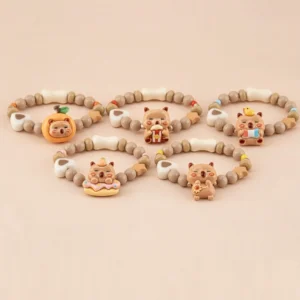 Sammlung von fünf elastischen Capybara Perlenarmbändern für Kinder mit glänzenden Emaille Charms in Popcorn-, Donut-, Sonnenblumen- und Obst-Designs auf beigem Hintergrund