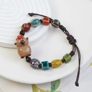 Nahaufnahme von zwei verstellbaren gewebten Capybara Armbändern mit glasierten Keramik-Capybara-Charms in braunen und beigen Tönen, Design 2