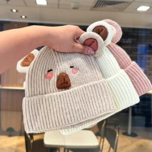 Drei verschiedene Farben von gestrickten Capybara Beanies für Kleinkinder mit großen 3D Ohren und gestickten rosafarbenen Wangen