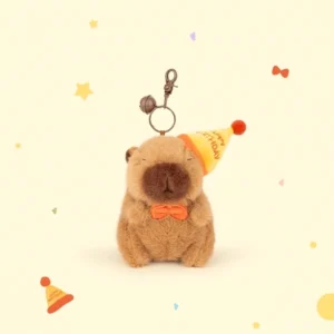 Vorderansitz des sitzenden Capybara Plüsch-Schlüsselanhängers mit gelbem Happy Birthday Partyhut und orangem Fliegentuch