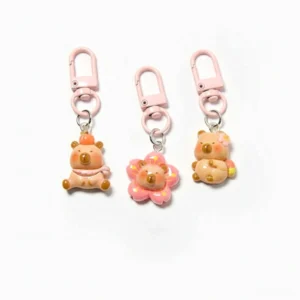 Einzelner Sakura Capybara Taschenanhänger in sitzender Pose mit orangenem Accessoire