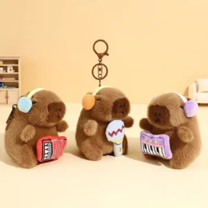 drei capybara plüsch schlüsselanhänger mit ohrenschützern mit rotem akkordeon, blauem mikrofon und lila tastatur, capybara plüsch-anhänger