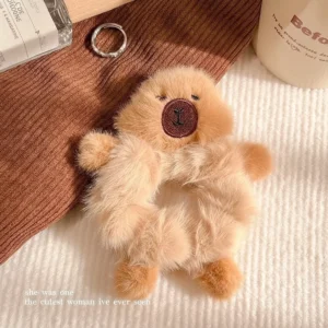 Flauschiger beige Capybara Scrunchie mit kleinen 3D Armen und Beinen aus der Vogelperspektive, der wie eine Umarmung um Haar oder Handgelenk sitzt