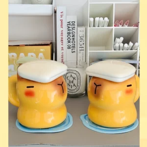 Gelbe Capybara Keramiktasse in Form eines badenden Capybaras mit weißem handtuchförmigem Deckel und entspanntem schlafendem Gesicht
