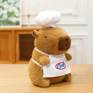 Braunes Koch Capybara Kuscheltier mit weißer Kochmütze und Schürze mit Cook Logo steht auf einem Tisch