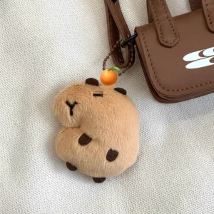 Bohnenförmiger Capybara Plüsch-Schlüsselanhänger mit Quietscher hängt an einer weißen Canvas-Tasche