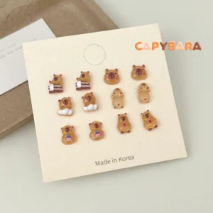 Kollektion von sechs Paaren mini capyba ohrenecker mit verschiedenen motiven wie schlafender capybara, badender capybara und snack capybara